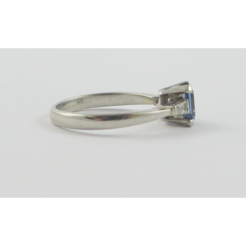 117 - A platinum sapphire and diamond ring  set with a claw set emerald cut sapphire  and tapered baguette... 