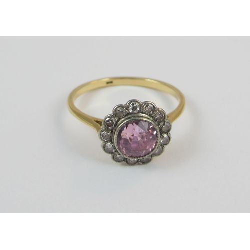 22 - A pink sapphire and diamond 18ct dress ring. The central pink sapphire of approx 6.4mm in millgrain ... 