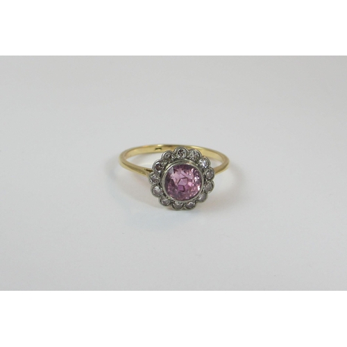 22 - A pink sapphire and diamond 18ct dress ring. The central pink sapphire of approx 6.4mm in millgrain ... 