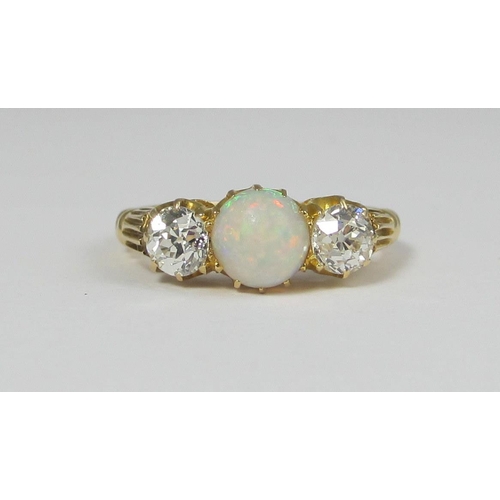 69 - A diamond and opal three stone ring in classic crown setting  mounted in 18ct yellow gold  the centr... 