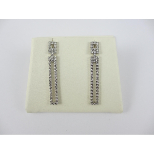 83 - A pair of long diamond set earrings in 18ct white gold. 47 pave set brilliant cut diamonds in each e... 