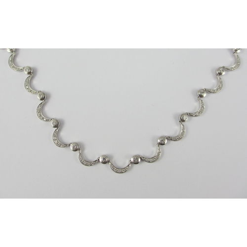 85 - An 18ct white gold diamond set crescent moon necklace. Necklace made up of thirty one crescent moon ... 