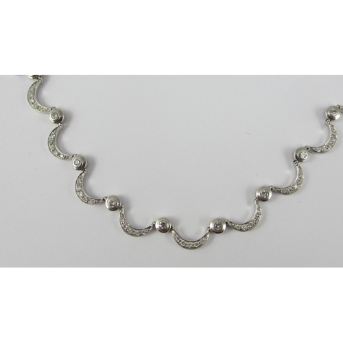 85 - An 18ct white gold diamond set crescent moon necklace. Necklace made up of thirty one crescent moon ... 