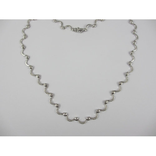 85 - An 18ct white gold diamond set crescent moon necklace. Necklace made up of thirty one crescent moon ... 