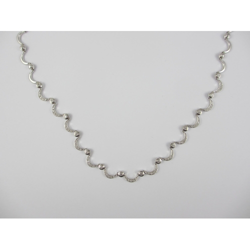 85 - An 18ct white gold diamond set crescent moon necklace. Necklace made up of thirty one crescent moon ... 