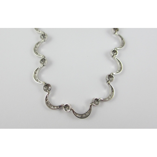 85 - An 18ct white gold diamond set crescent moon necklace. Necklace made up of thirty one crescent moon ... 