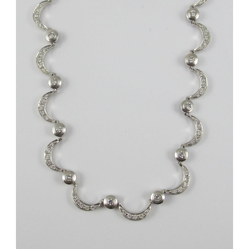 85 - An 18ct white gold diamond set crescent moon necklace. Necklace made up of thirty one crescent moon ... 