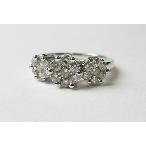 87 - A fourteen carat white gold triple diamond cluster ring