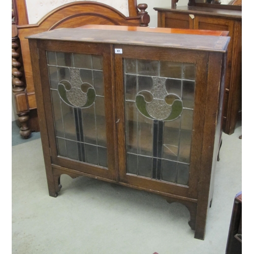 871 - An Art Nouveau oak two door bookcase. The doors decorated with a stained and leaded glass panel 98cm... 