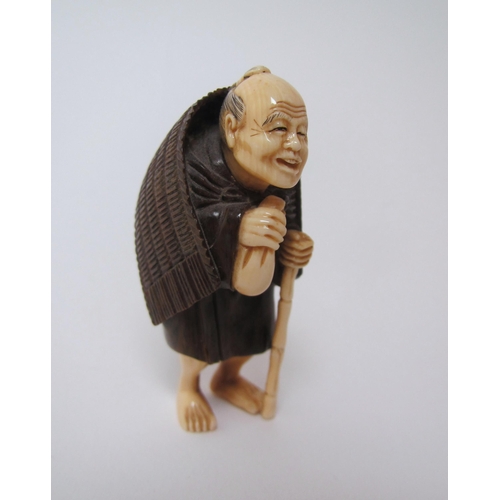 658 - A Japanese ivory and hardwood netsuke of a traveller