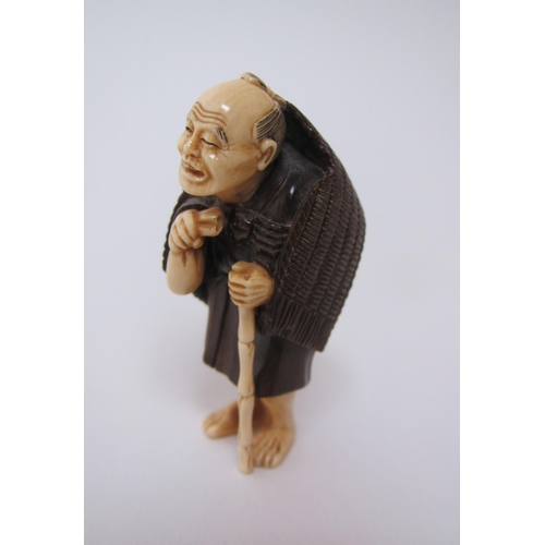 658 - A Japanese ivory and hardwood netsuke of a traveller