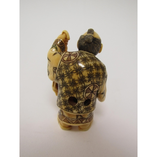 659 - A Japanese ivory netsuke of a man holding a bird cage and a stick