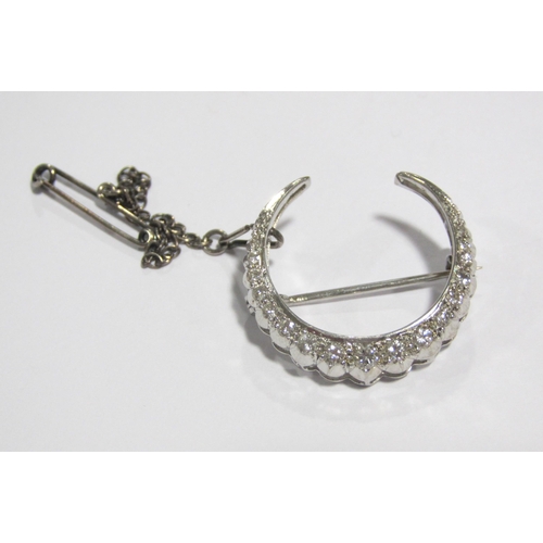 61 - A white metal diamond set crescent shaped brooch