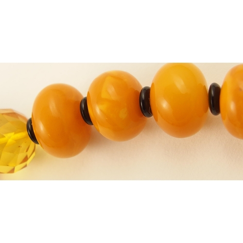 107 - Item 12. A mixed amber coloured bead necklace