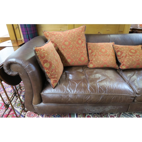 102 - A 20th century brown leather three seater settee red patterned cushions on shaped feet terminating i... 