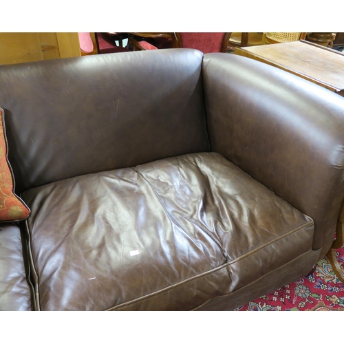 102 - A 20th century brown leather three seater settee red patterned cushions on shaped feet terminating i... 