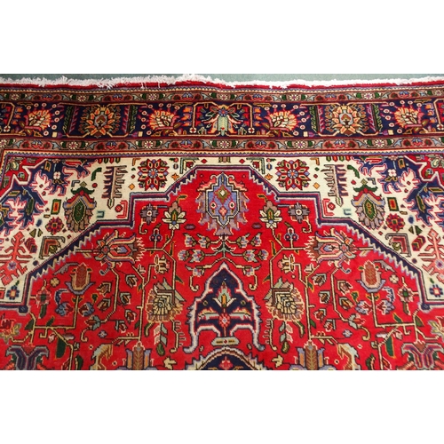 18 - A red ground Kashan rug with dark blue central medallion, white spandrels and a multicoloured flower... 