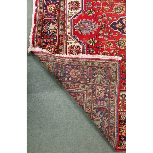 18 - A red ground Kashan rug with dark blue central medallion, white spandrels and a multicoloured flower... 