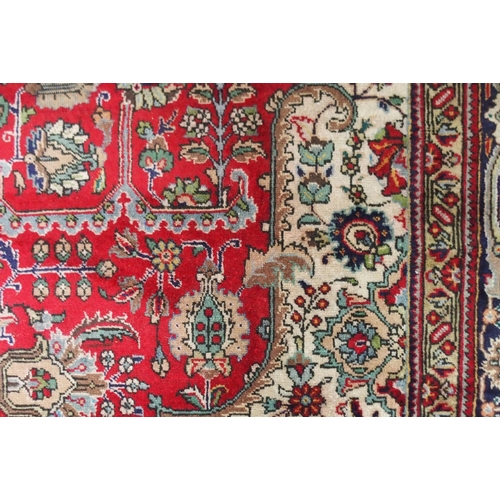 19 - A red ground Tabriz rug with dark blue central medallion, cream spandrels and dark blue borders, 347... 