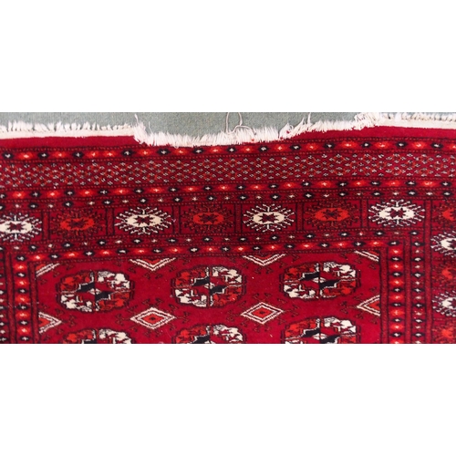 20 - A red ground Bokhara rug with all-over lozenge design, 181cm long x 126cm wide