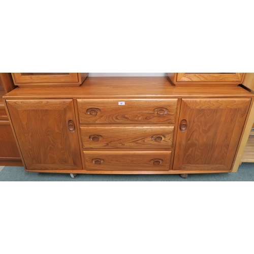 67 - A 20th century elm and beech Ercol sideboard with pair of glazed cabinets flanking central open shel... 