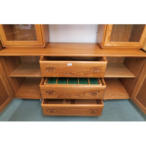 67 - A 20th century elm and beech Ercol sideboard with pair of glazed cabinets flanking central open shel... 