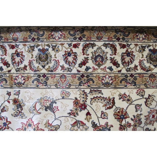 135 - A cream ground machine made Kashmiri rug with all-over floral design and flower head borders, 300cm ... 