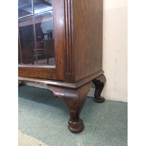 104 - A 20th century oak glazed bookcase with pair of leaded glass doors on cabriole supports, 128cm high ... 