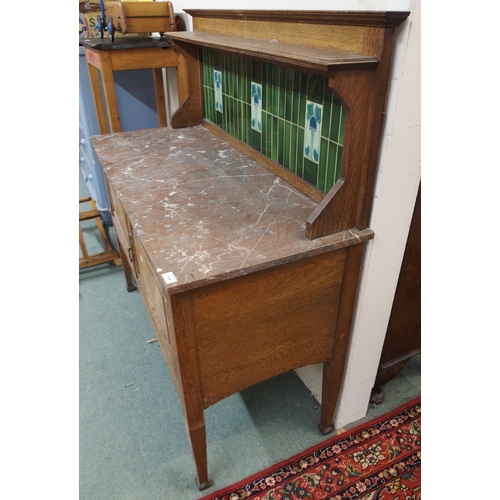 114 - A late Victorian oak arts and crafts washstand with green tiled splashback over marble top above pai... 