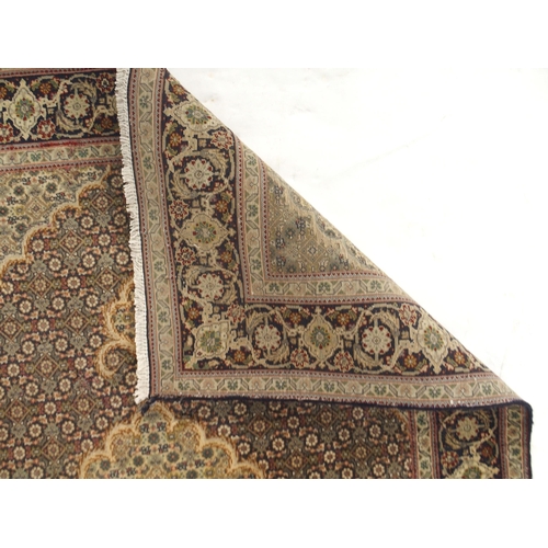 150 - A multicoloured ground Tabriz rug with green central medallion, matching spandrels and a dark blue f... 