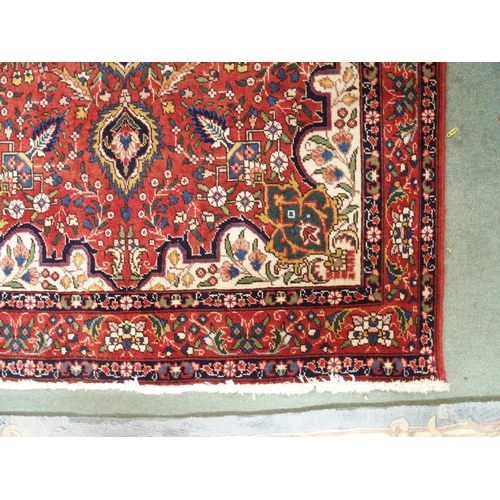 151 - A red ground Tabriz rug with multicoloured central medallion, cream spandrels, floral patterned grou... 