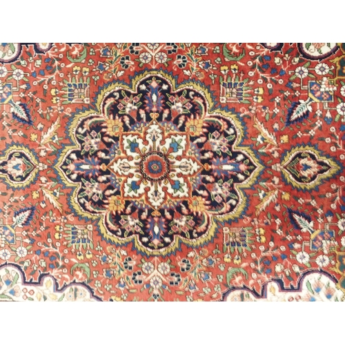 151 - A red ground Tabriz rug with multicoloured central medallion, cream spandrels, floral patterned grou... 