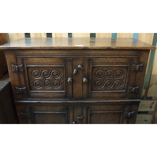 64 - A 20th century oak side cabinet with pair of carved cabinet doors over pair of panel doors on block ... 