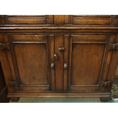 64 - A 20th century oak side cabinet with pair of carved cabinet doors over pair of panel doors on block ... 