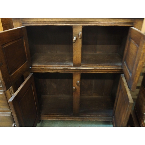 64 - A 20th century oak side cabinet with pair of carved cabinet doors over pair of panel doors on block ... 