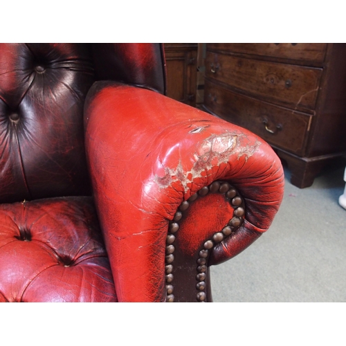 77 - A 20th century red leather button back upholstered Chesterfield style wing back armchair, 109cm high... 