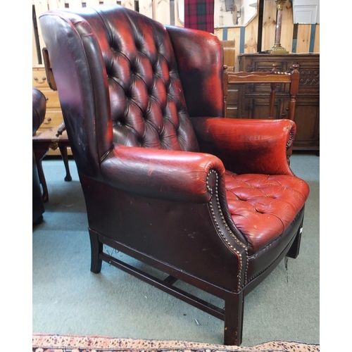 77 - A 20th century red leather button back upholstered Chesterfield style wing back armchair, 109cm high... 