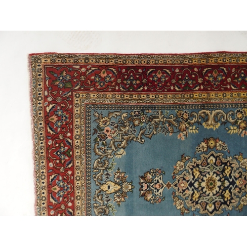 91 - A light blue ground Qom rug with dark blue floral medallion, matching spandrels and red flower head ... 