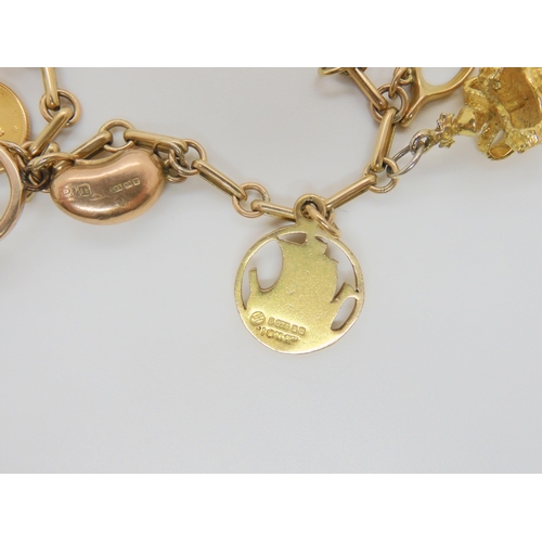 704 - A 9ct gold charm bracelet with five 9ct hallmarked charms to include a Scouting swastika charm, a Jo... 