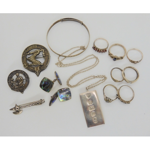 736 - A collection of silver and white metal items to include an ingot pendant, clan badges, rings, paua s... 