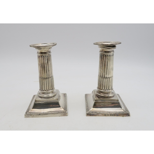 286D - A collection of silver including a pair of silver candlesticks, modelled as Doric columns, on a slop... 