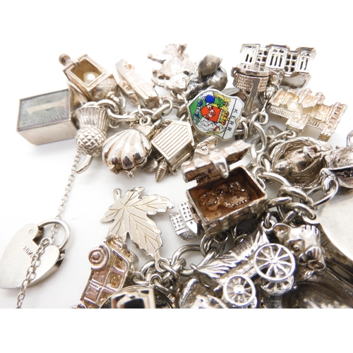 580 - A silver and white metal extensive charm bracelet, to include opening charms, treasure chest, pig, w... 