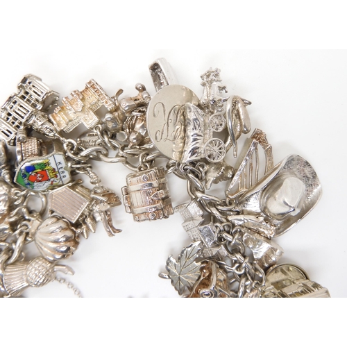 580 - A silver and white metal extensive charm bracelet, to include opening charms, treasure chest, pig, w... 