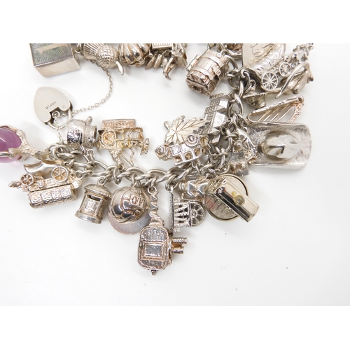 580 - A silver and white metal extensive charm bracelet, to include opening charms, treasure chest, pig, w... 