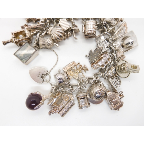 580 - A silver and white metal extensive charm bracelet, to include opening charms, treasure chest, pig, w... 