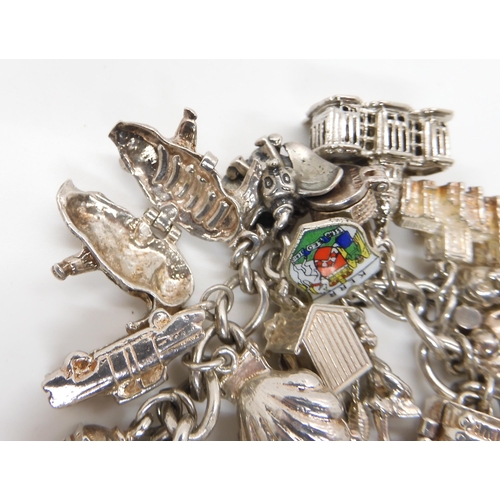 580 - A silver and white metal extensive charm bracelet, to include opening charms, treasure chest, pig, w... 