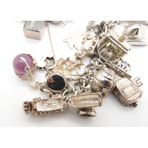 580 - A silver and white metal extensive charm bracelet, to include opening charms, treasure chest, pig, w... 