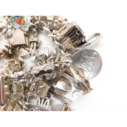 580 - A silver and white metal extensive charm bracelet, to include opening charms, treasure chest, pig, w... 