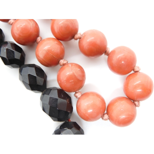 602 - A string of coral beads, each bead approx 11.5mm, weight 32.5gms, together with a dark cherry amber ... 