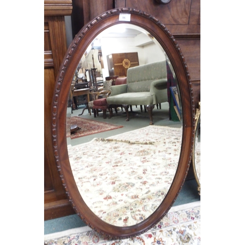 86 - A Victorian mahogany framed oval wall mirror, 59cm high x 94cm wide, a copped framed bevelled glass ... 